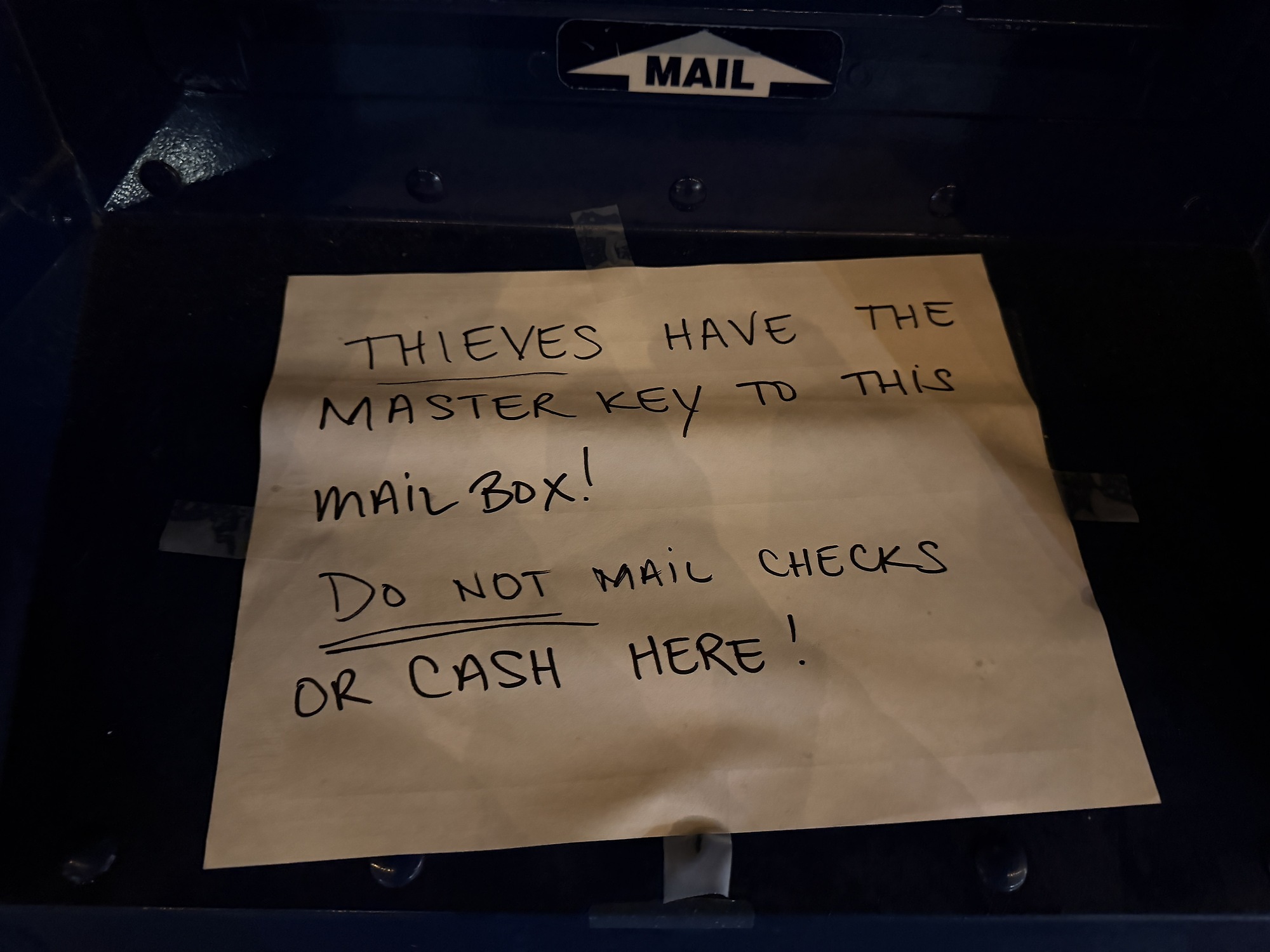 Ein Postbriefkasten mit aufgeklebter Warnung.