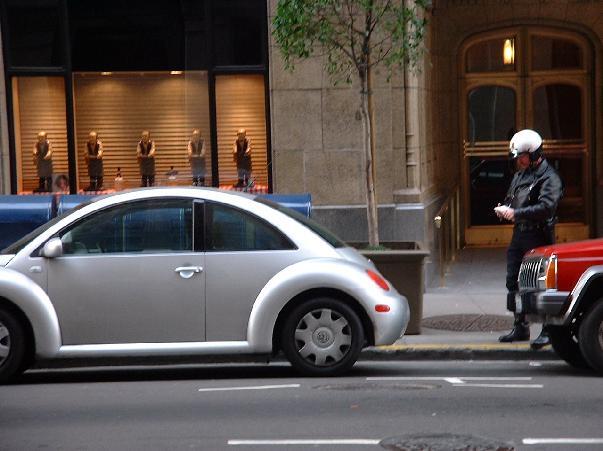 Ein Motorrad-Bulle schreibt einen neuen VW-Käfer auf.